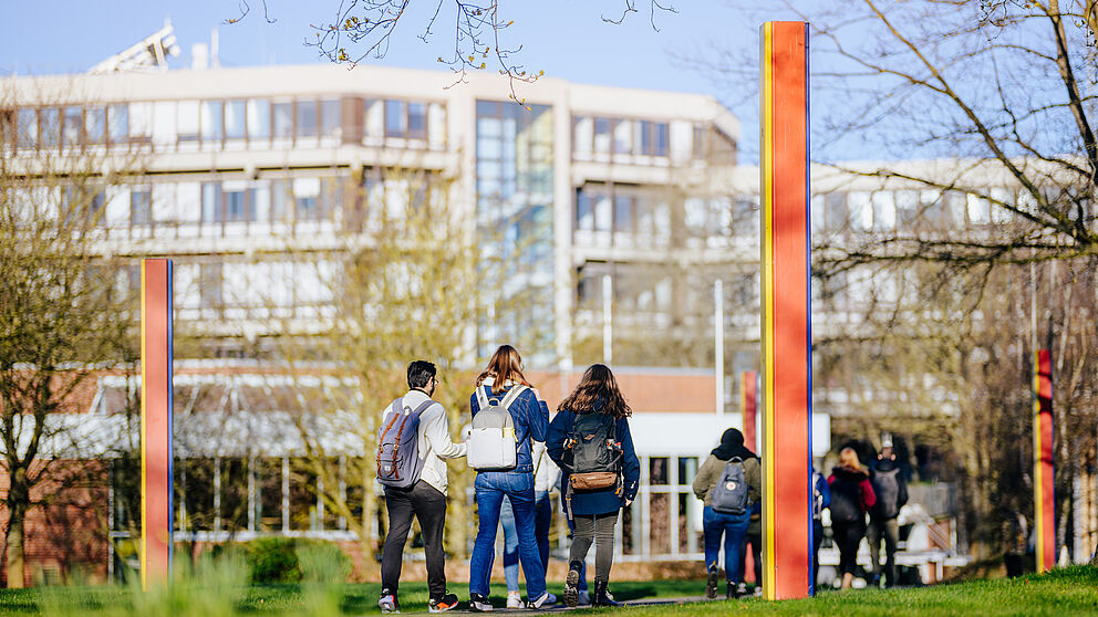 Personengruppe und farbige Stelen auf dem Campus der Universität Paderborn.